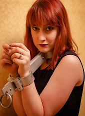 Redhead has her arms locked firmly in a rigid iron